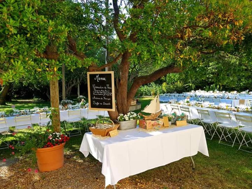 Réception champêtre à l'exterieur dans un jardin, menu accroché à un arbre au dessus du buffet