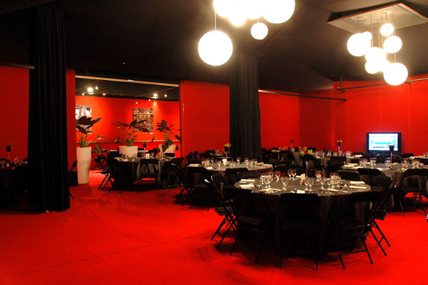 Salle préparée et tables dressées en noir et rouge pour un évènement